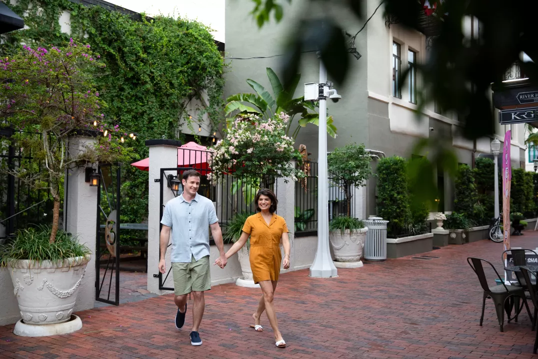A couple holding hands walking down a sidewalk
