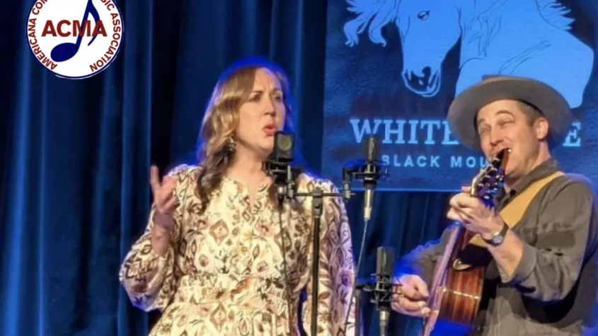 Music duo "Songs of the Folk" onstage with ACMA logo in corner