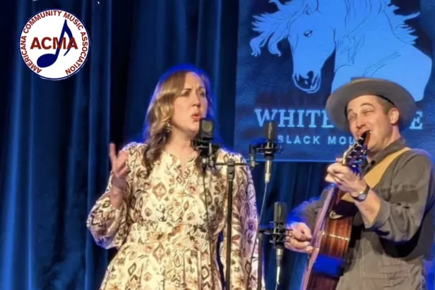 Music duo "Songs of the Folk" onstage with ACMA logo in corner
