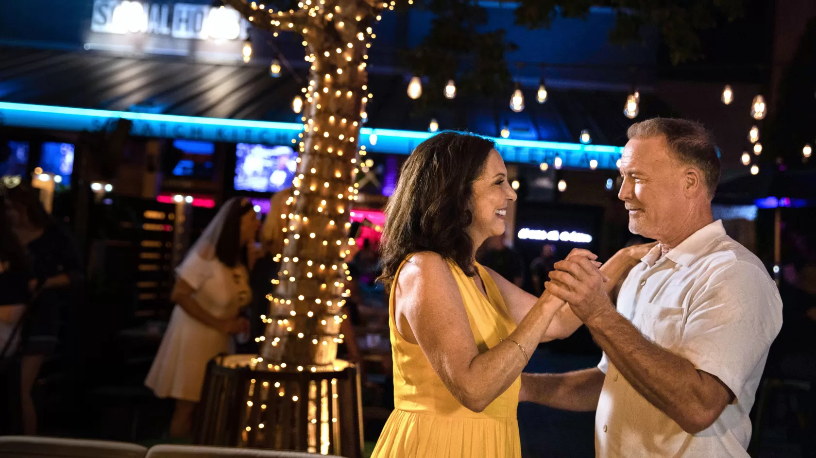 A man and a woman dance at an outdoor bar