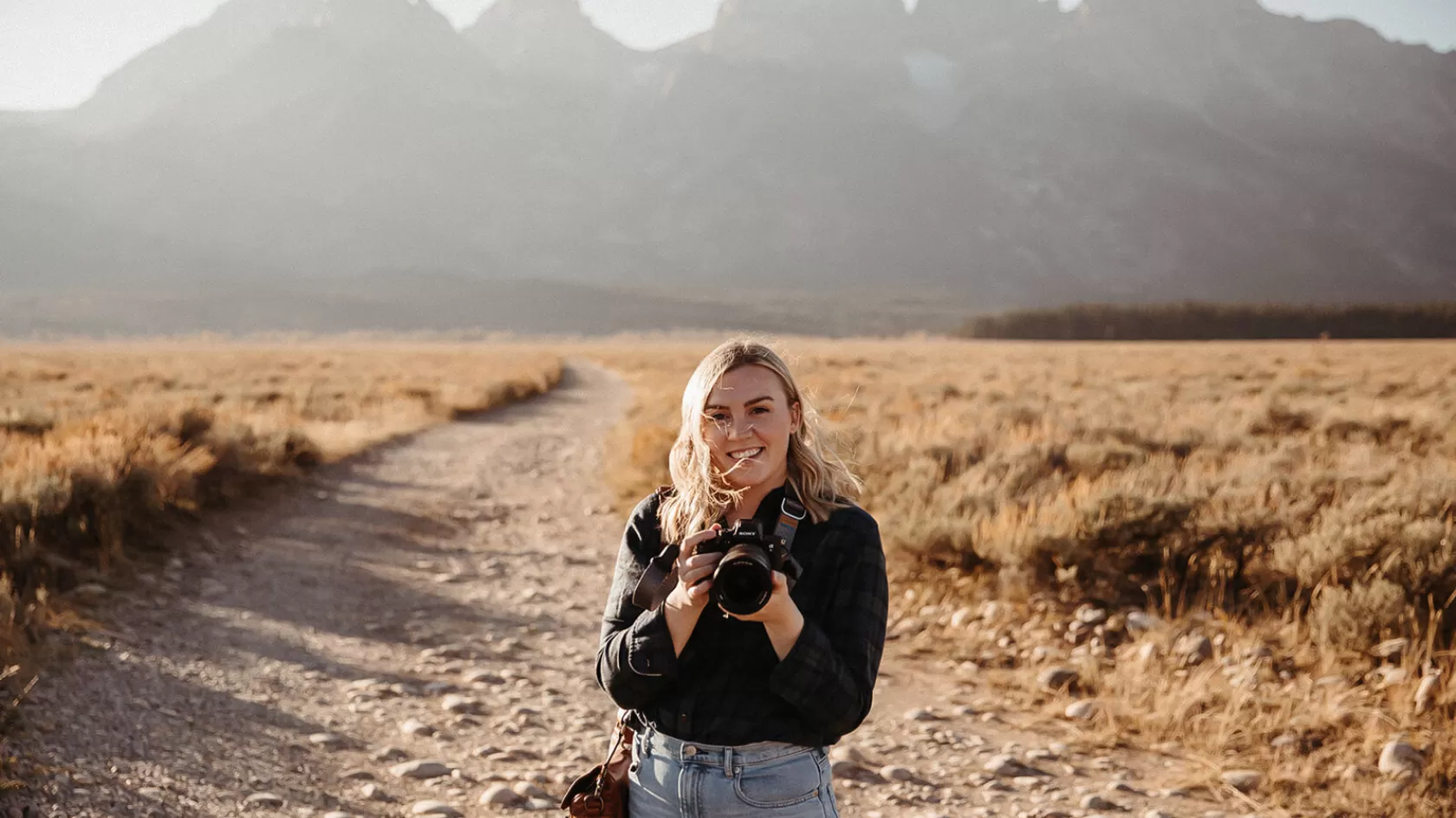 a photo of a woman holding a camera lens in a field