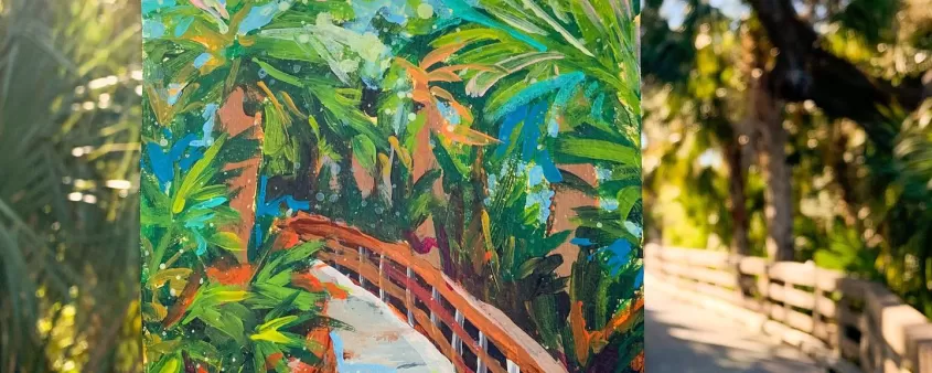 hand holding a small piece of artwork in front of tropical setting