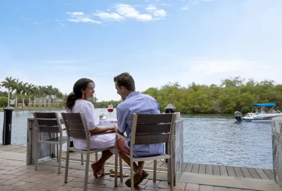 a couple sitting at a table by water