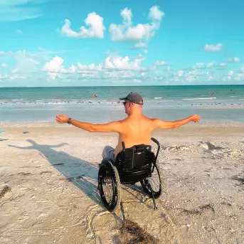 guy sitting in wheelchair on the beach